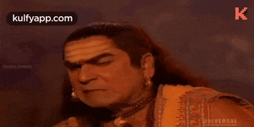 a man with long hair is looking at the camera .