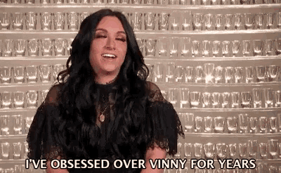 a woman is standing in front of a wall of wine glasses and saying i 've obsessed over vinny for years