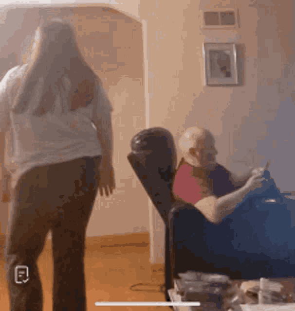 a woman is standing next to a man sitting on a couch