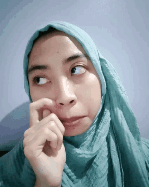 a woman wearing a green hijab looks to the side