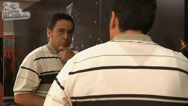 a man is looking at himself in a mirror with a sign behind him that says ' x factor ' on it