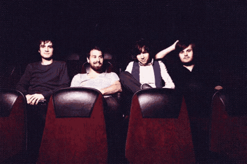 a group of people are sitting in red seats in a dark theater