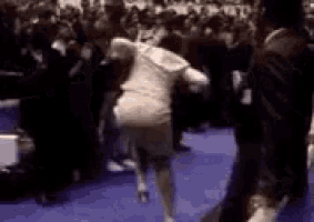 a blurry picture of a woman dancing in front of a crowd of people .