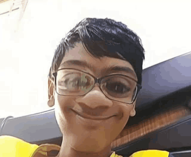 a young boy wearing glasses and a life jacket is smiling .
