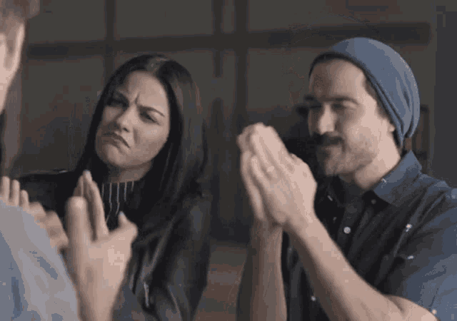 a man and a woman are clapping their hands in a room