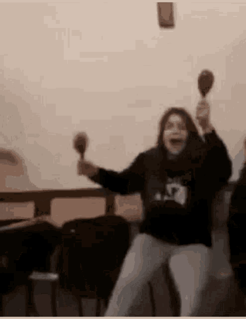 a woman is holding maracas in her hands and screaming .