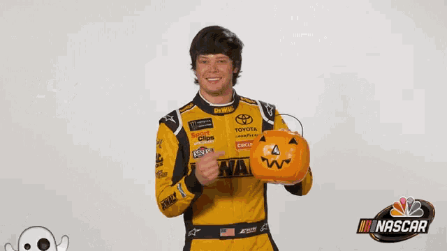 a man in a nascar uniform holds a pumpkin