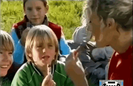 a group of young boys are sitting around a table eating ice cream .