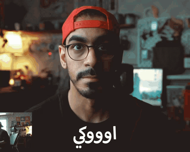 a man wearing glasses and a red hat is giving a thumbs up in arabic