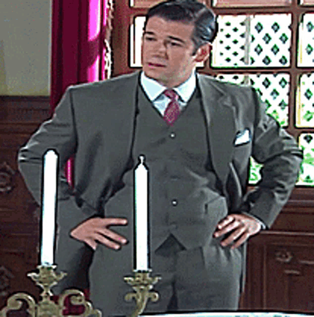 a man in a suit and tie stands in front of a candle holder