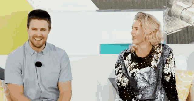 a man and a woman are sitting next to each other on a couch and smiling