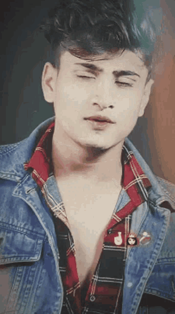 a young man wearing a denim jacket and plaid shirt