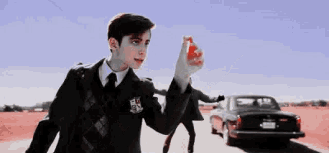 a young boy in a suit and tie is holding a red object in his hand .