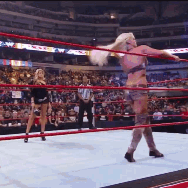 a woman is standing in a wrestling ring with a referee watching
