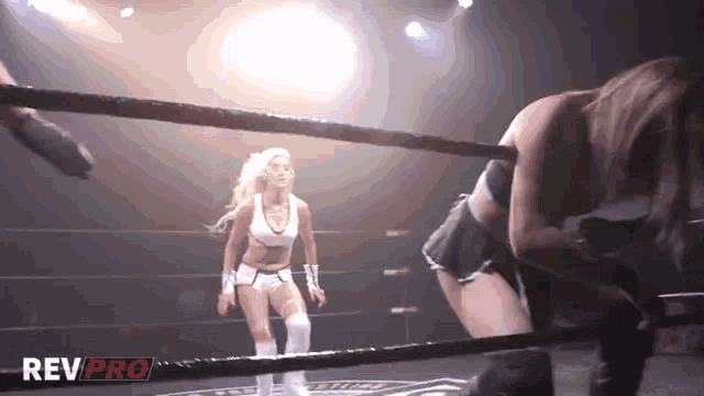 two women in a wrestling ring with rev pro written on the bottom