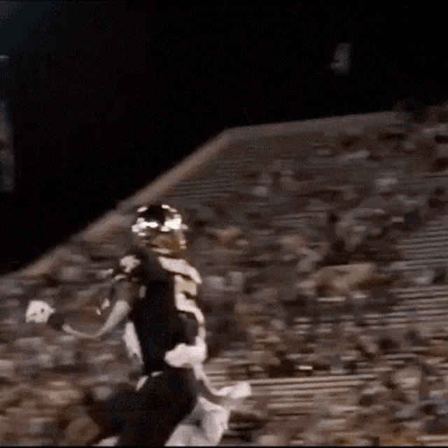 a football player is running on a field with a crowd in the background .