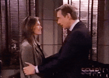 a man in a suit and tie is hugging a woman in front of a screen that says seven ad