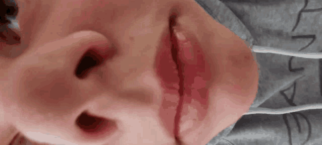 a close up of a person 's face with red lips and a gray shirt .