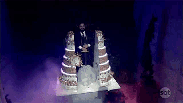 a man and woman are standing in front of a wedding cake .