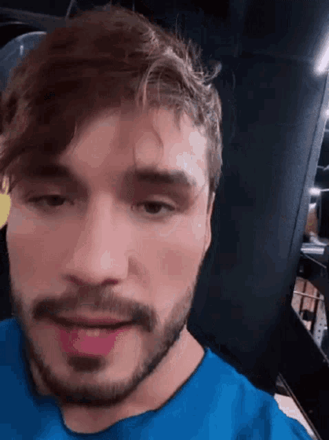 a man with a beard wearing a blue shirt looks at the camera