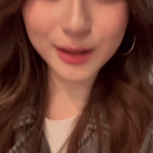 a close up of a woman 's face with her mouth open and earrings .