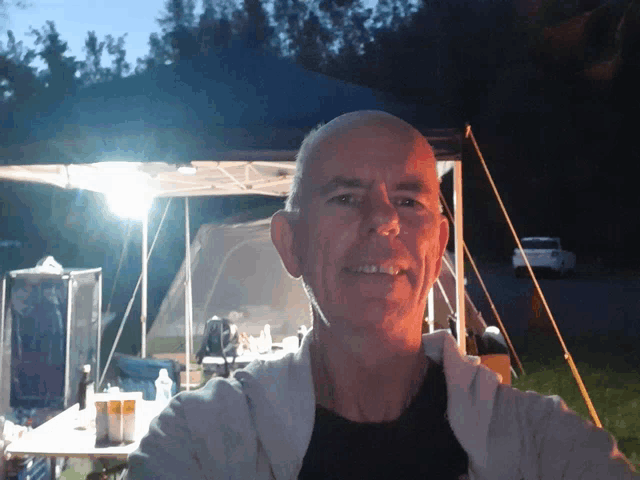 a man is standing in front of a tent and smiling for the camera