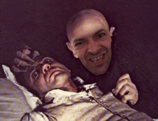 two men are posing for a picture next to a painting of a man laying down