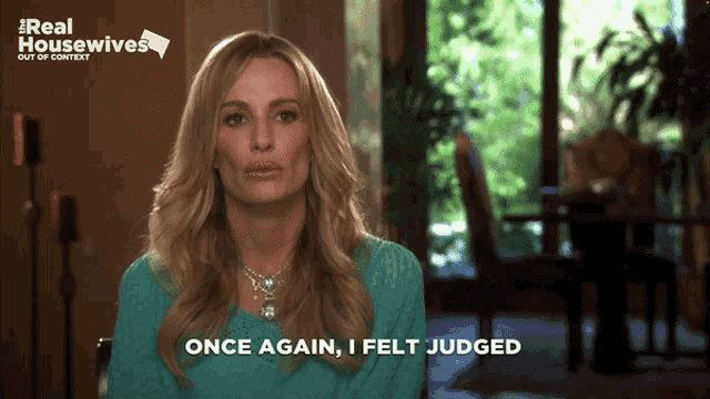a woman says " once again i felt judged " in front of a sign that says real housewives