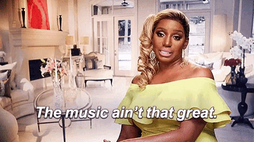 a woman in a yellow dress is sitting in a living room and saying the music ain 't that great .