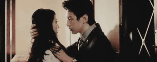 a man in a suit and tie is kissing a woman on the forehead .