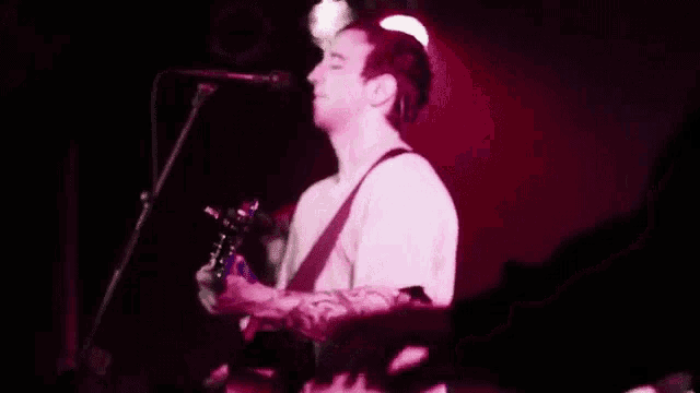 a man is playing a guitar in front of a microphone on a stage .