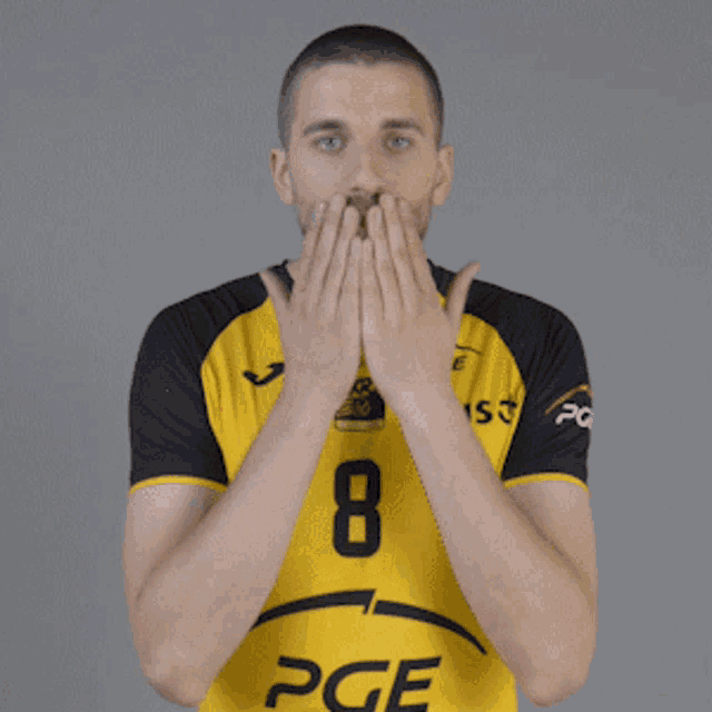 a man wearing a yellow pge jersey holds his hands up in the air