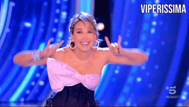 a woman in a pink and black dress is dancing on a stage with the words viperissima behind her