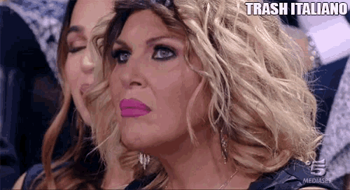 two women are sitting next to each other with trash italiano written on the bottom right