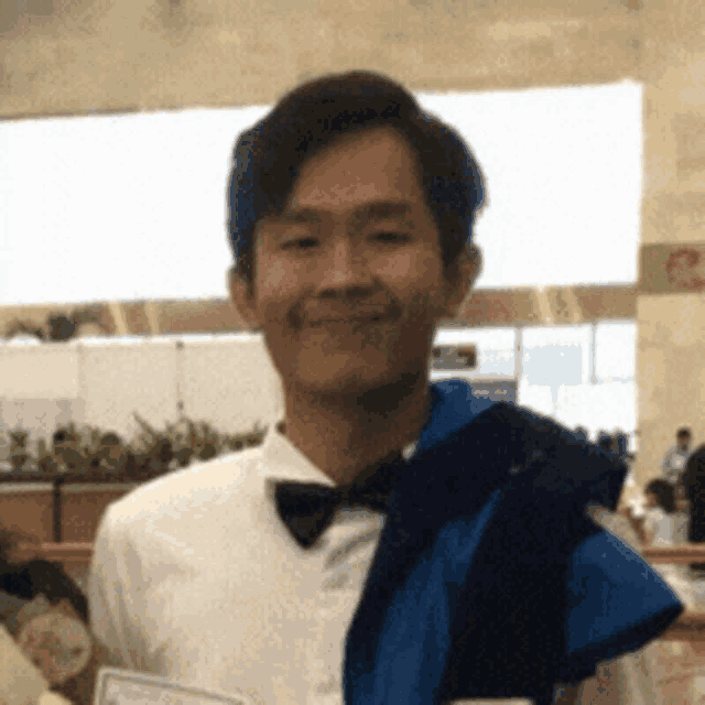 a man wearing a white shirt and a bow tie is holding a diploma .