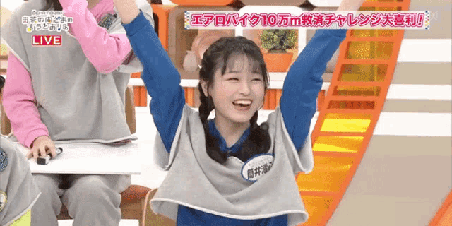 a girl with her arms in the air and the word live on the bottom right