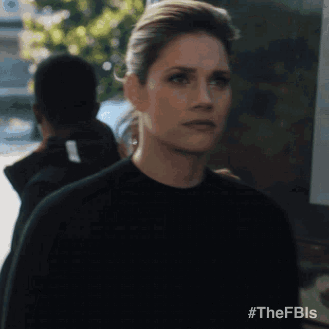 a woman in a black sweater is standing in front of a sign that says #thefbls