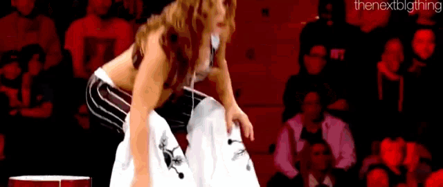 a woman is kneeling down in front of a crowd in a stadium .
