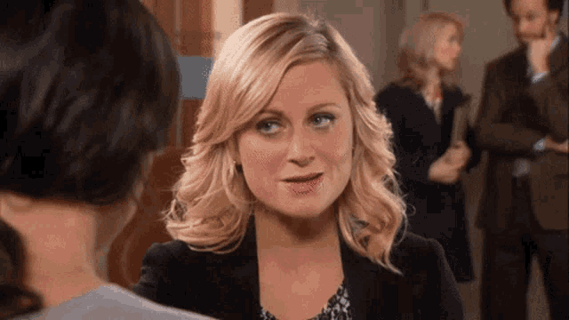 a woman in a black jacket is talking to a woman in a gray shirt