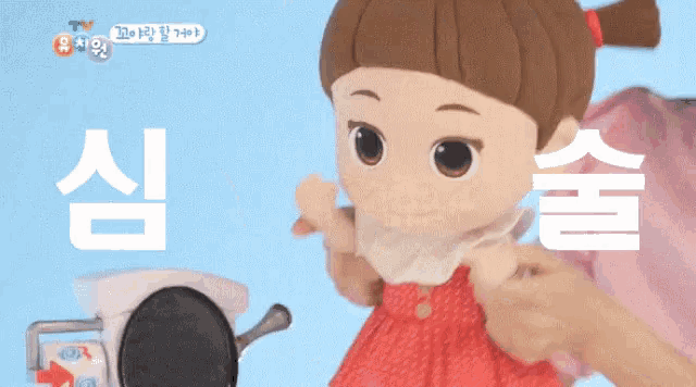 a doll with a red dress is being held by a person in front of a toilet paper dispenser