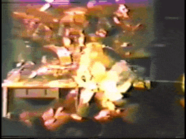a group of people are standing around a table in a room with a lot of fire coming out of it