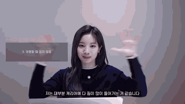 a woman in a blue sweater is waving her hand in front of a screen that says 3