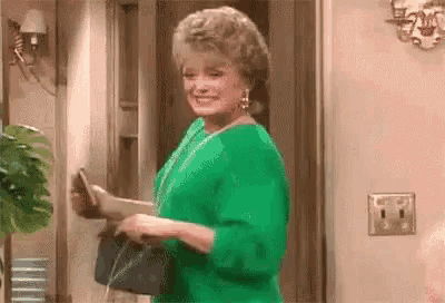 a woman in a green dress is holding a black purse .