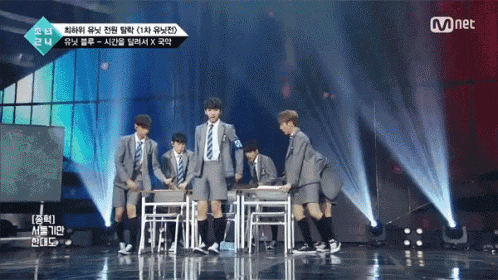 a group of young men in school uniforms on a stage with mnet written on the bottom right