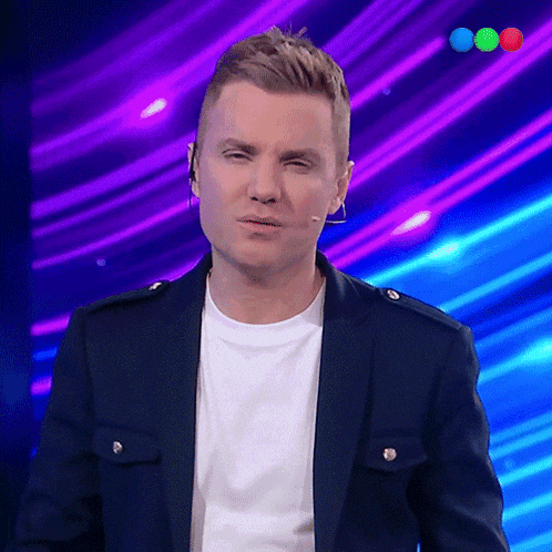 a man wearing a blue jacket and a white shirt stands in front of a purple background