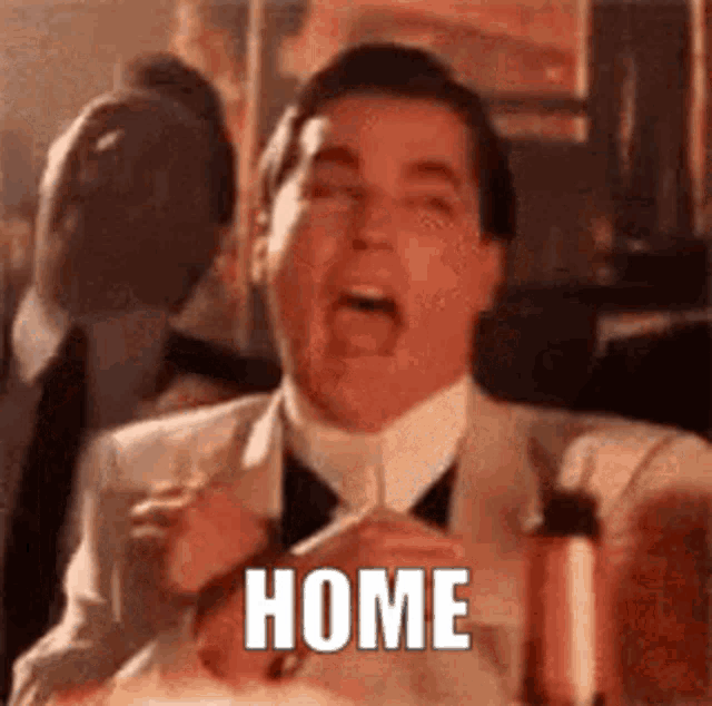 a man in a suit and tie is sitting at a table with his mouth open and the word home written on it .