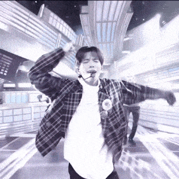 a man wearing a plaid shirt and a white shirt is dancing with his arms outstretched