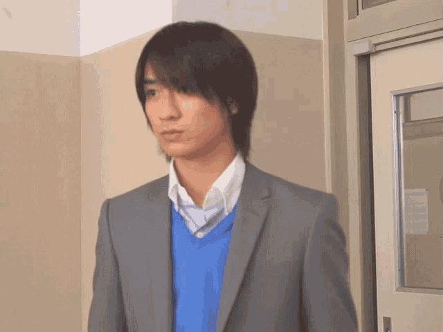 a young man in a suit and blue sweater