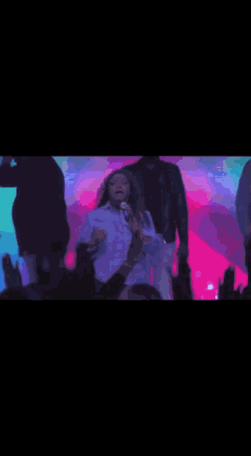a woman is dancing in front of a crowd of people at a concert