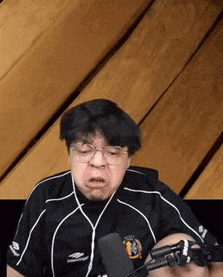 a man wearing glasses is sitting in front of a microphone .